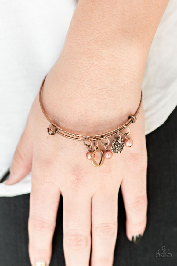 Paparazzi Truly True Love - Copper - Bracelet
A delicately hammered copper wire coils around the wrist, creating an adjustable-like bangle. Infused with a copper and topaz rhinestone fittings, a collection of pearly copper beads, a hammered copper disc, and a charming heart charm slides along the wrist in a whimsical fashion
